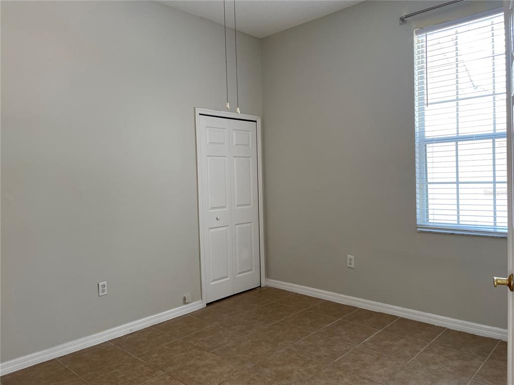 An empty room features light gray walls, tile flooring, a white closet door, and a window — 6813 WINSLOW STREET, SARASOTA, FL