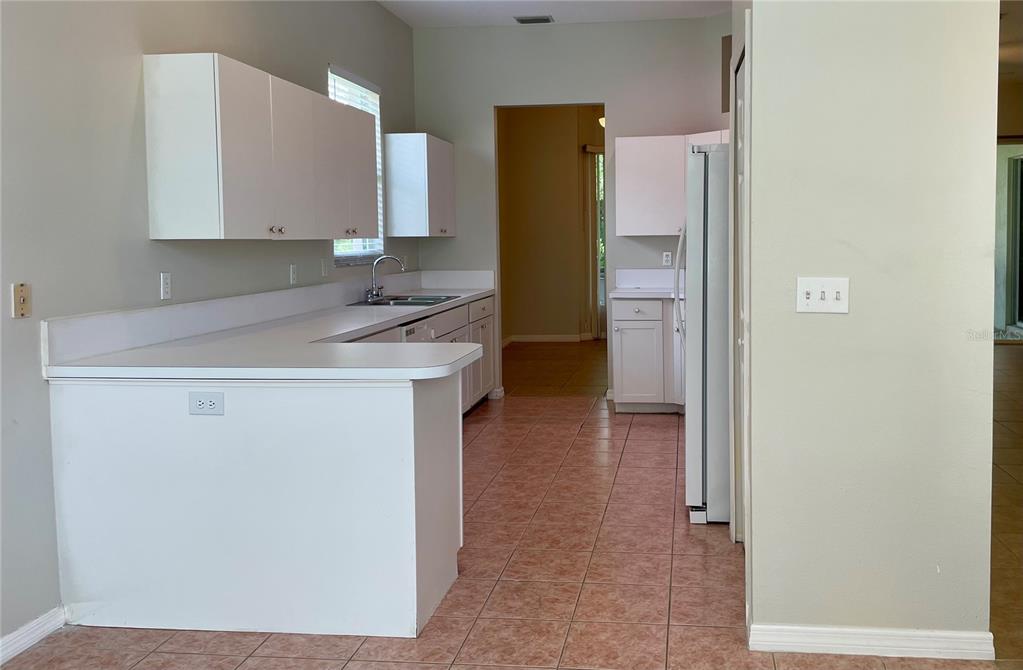 A kitchen features white cabinets, white countertops, and light-colored tile flooring — 6813 WINSLOW STREET, SARASOTA, FL