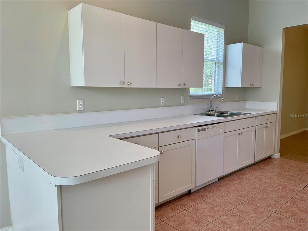 A kitchen features white cabinets, white countertops, a double sink, and light-colored tile flooring — 6813 WINSLOW STREET, SARASOTA, FL