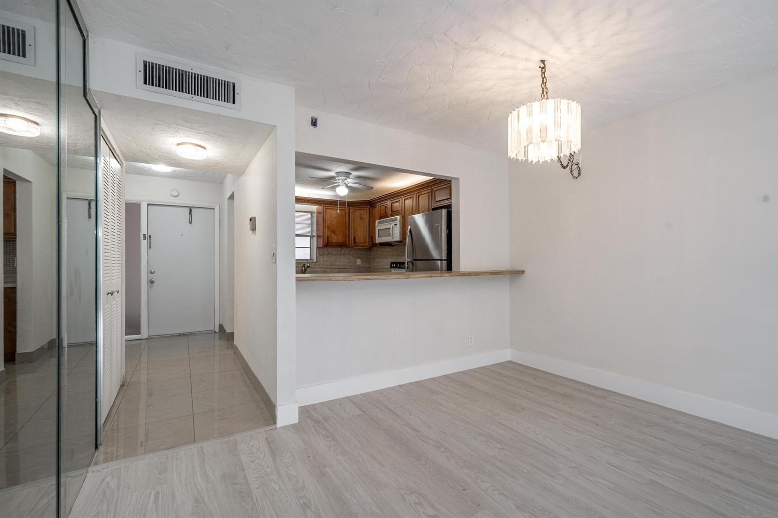 A dining area with light wood floors features a breakfast bar opening to the kitchen — 2551 Aragon Boulevard # 406, Sunrise FL 33322, SUNRISE, FL