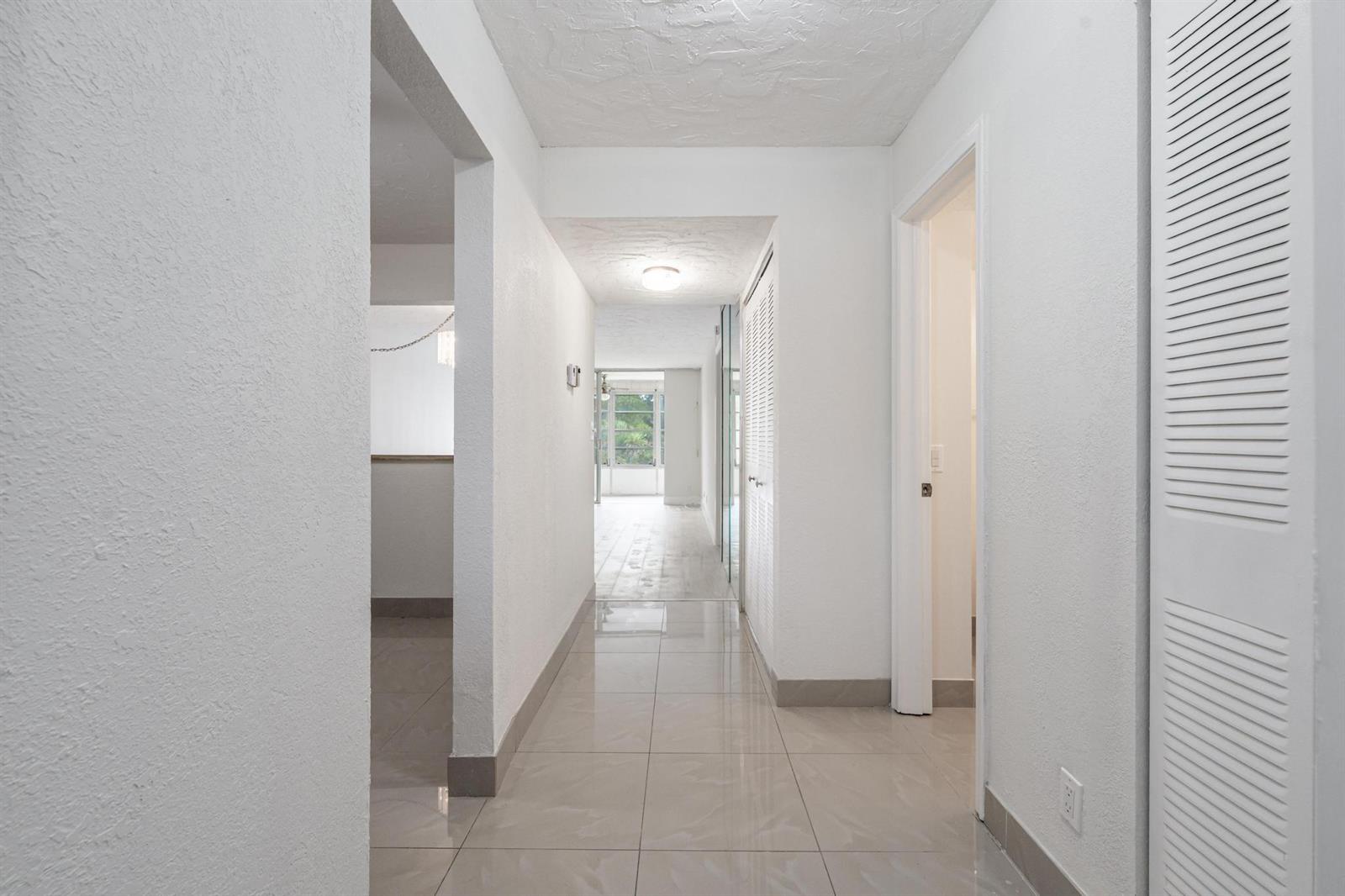 A bright hallway with light-colored tile flooring leads toward a windowed room — 2551 Aragon Boulevard # 406, Sunrise FL 33322, SUNRISE, FL
