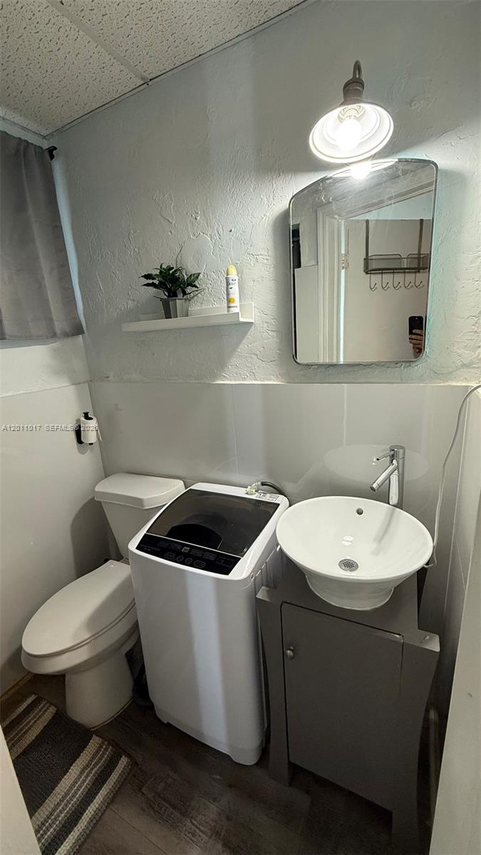 A small bathroom features a toilet, a portable washing machine, and a vessel sink vanity — 115 SE 2nd St # 2, Dania Beach FL 33004, DANIA BEACH, FL