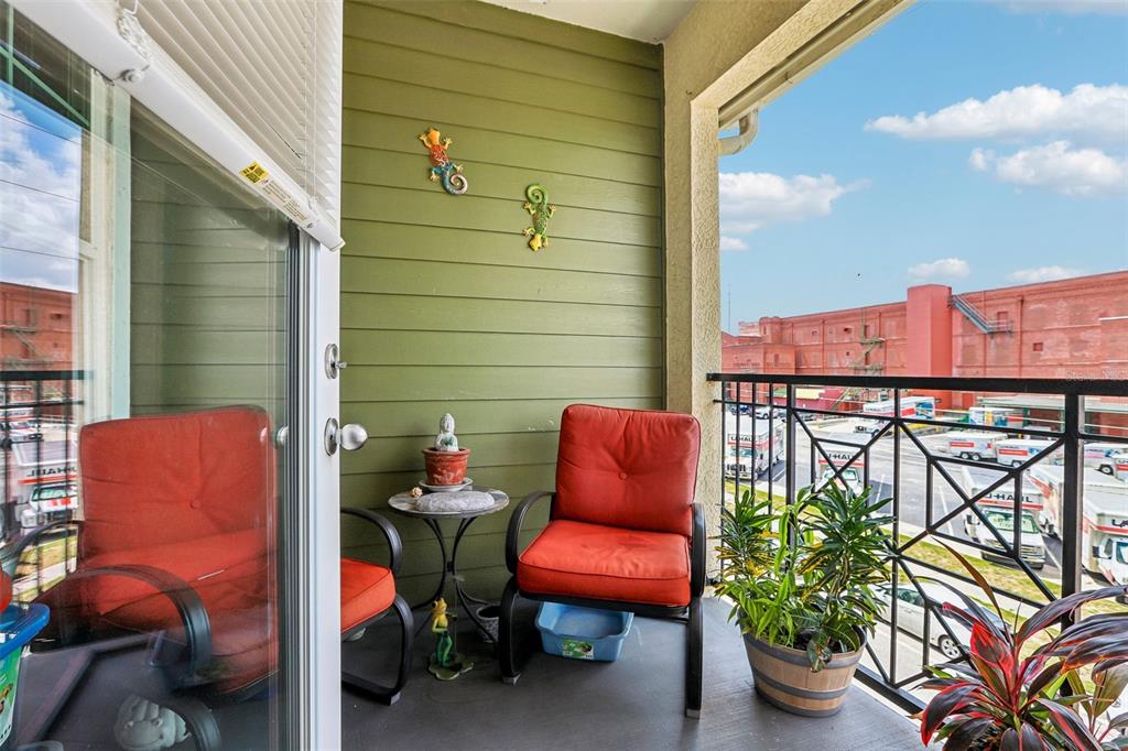 A balcony features two red chairs, a small table, and a view of a parking lot — 1810 E PALM AVENUE UNIT 5322, TAMPA, FL