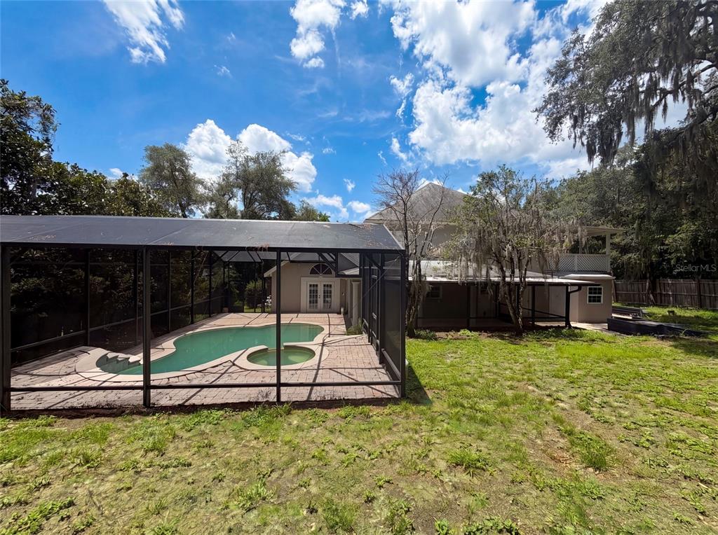 A backyard view featuring a screened-in swimming pool and a two-story house — 300 SPRUCEWOOD ROAD, LAKE MARY, FL