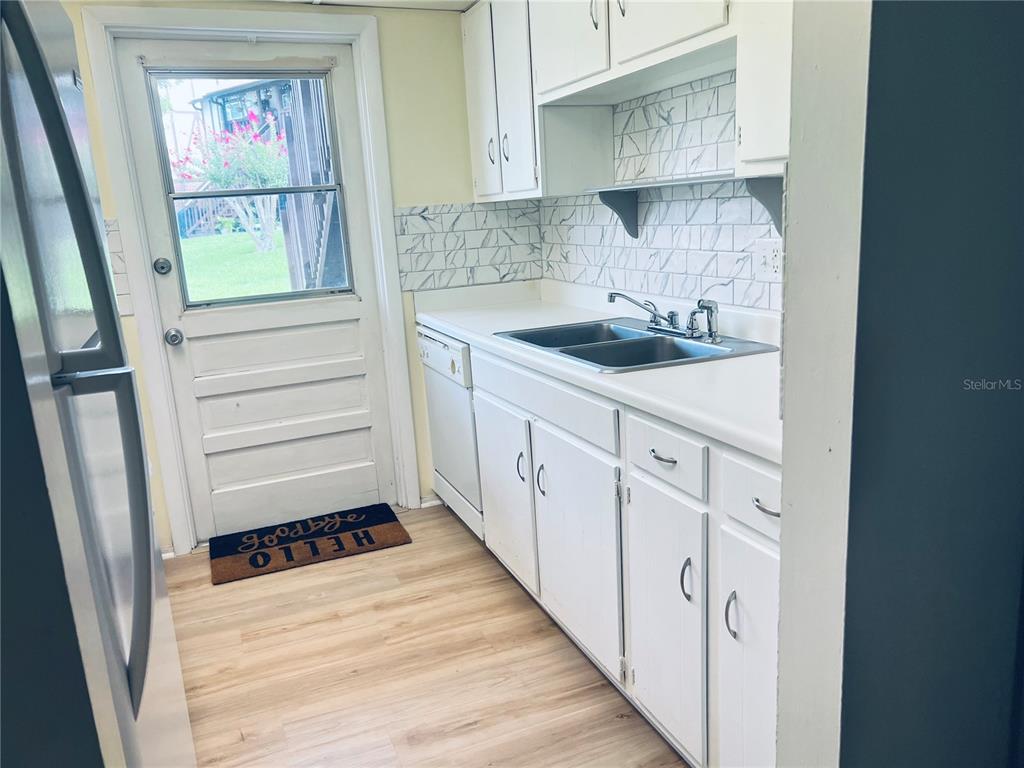 A kitchen features white cabinets, a double-basin sink, subway tile backsplash, and a glass-paneled door — 5467 HANSEL AVENUE UNIT H15, ORLANDO, FL