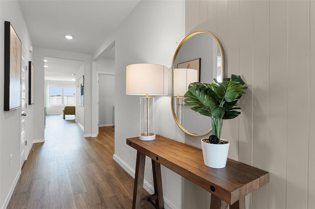 A hallway features wood-look flooring, a wooden console table, a lamp, and a round mirror — 363 BOTTLE BRUSH DRIVE, HAINES CITY, FL