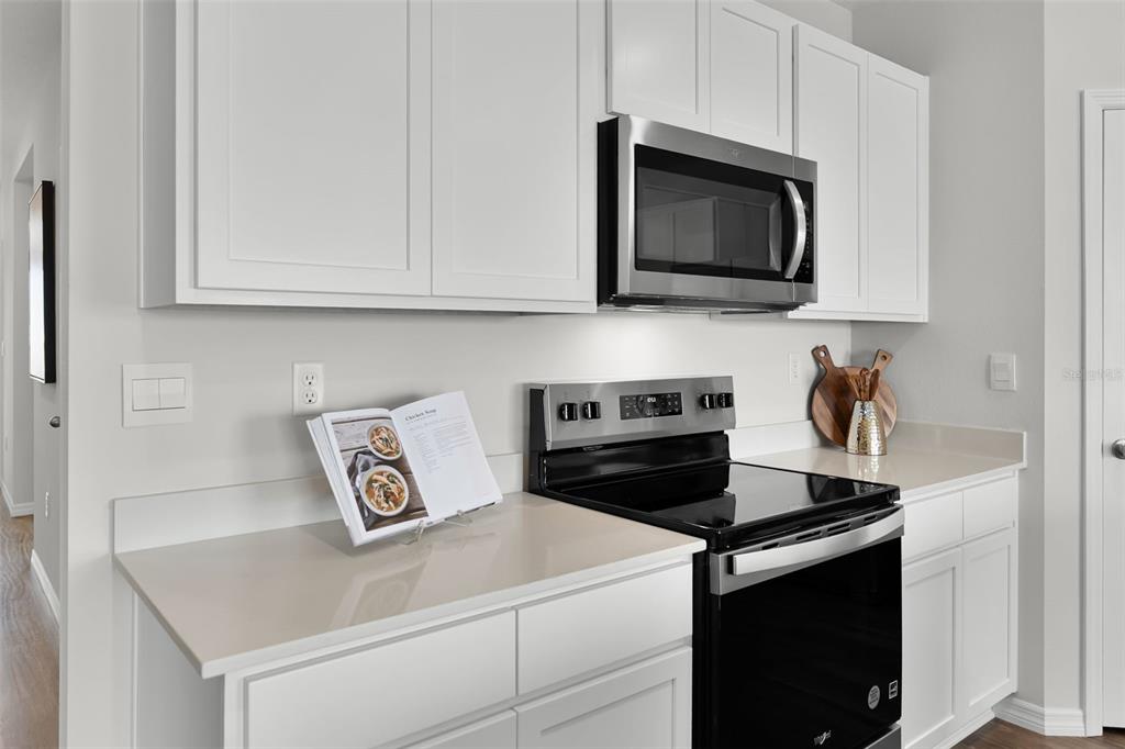 A kitchen features white cabinets, stainless steel appliances, and light-colored countertops — 363 BOTTLE BRUSH DRIVE, HAINES CITY, FL