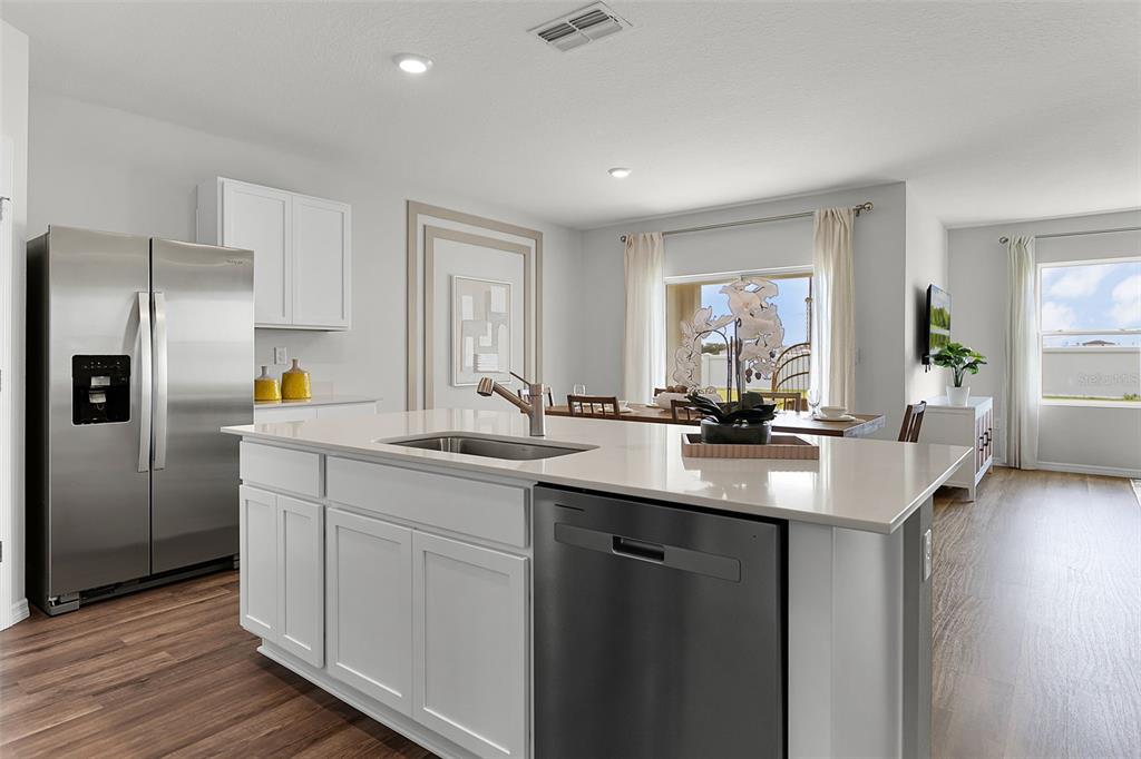 A modern kitchen features white cabinets, stainless steel appliances, and an island with a sink — 363 BOTTLE BRUSH DRIVE, HAINES CITY, FL