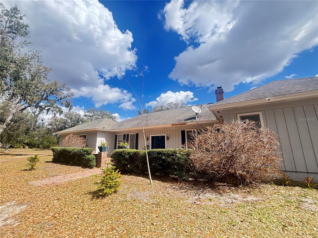 A single-story house with gray vertical siding, a brick walkway, and a large front yard — 1508 N ARCADIA AVENUE, ARCADIA, FL