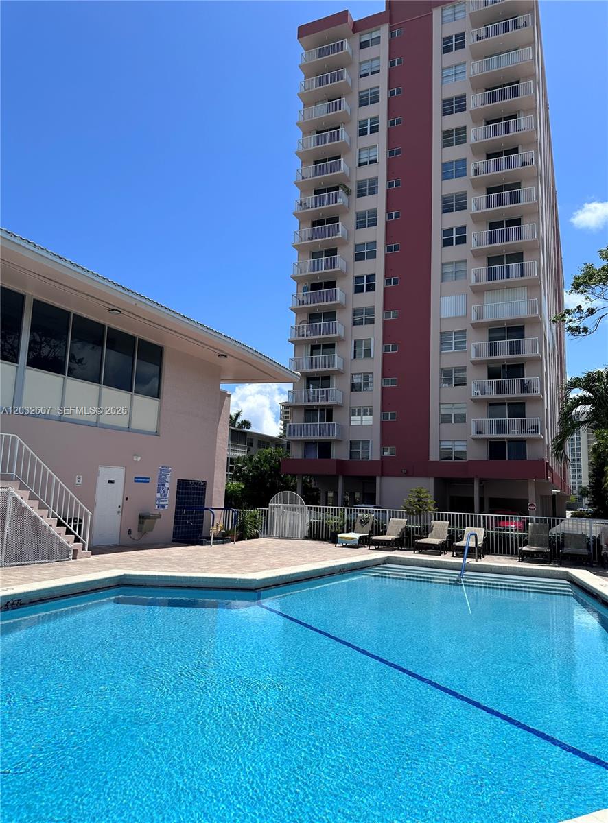 A swimming pool sits in front of a tall residential building with many balconies — 3161 S Ocean Dr # 803, Hallandale Beach FL 33009, HALLANDALE BEACH, FL