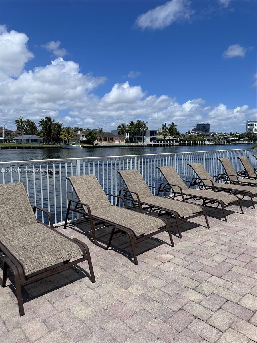 A row of lounge chairs sits on a paved patio overlooking a canal and houses — 3161 S Ocean Dr # 803, Hallandale Beach FL 33009, HALLANDALE BEACH, FL