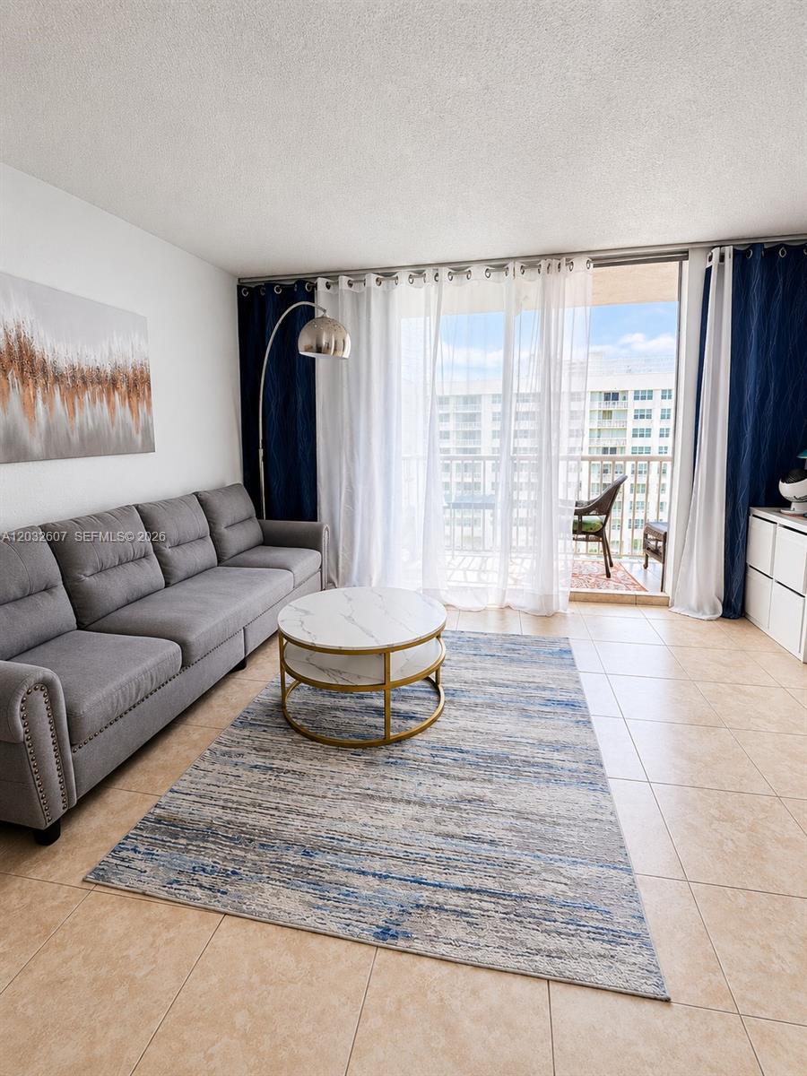 A living room features a gray sofa, a marble coffee table, and a balcony view — 3161 S Ocean Dr # 803, Hallandale Beach FL 33009, HALLANDALE BEACH, FL