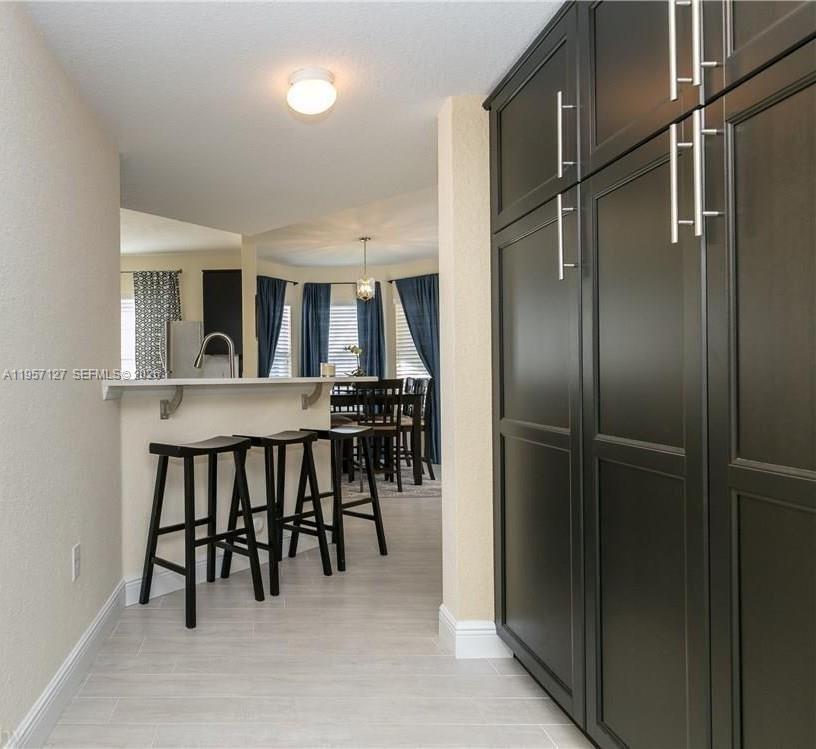 A kitchen features dark cabinetry, a breakfast bar with three stools, and a dining area — NORTH LAUDERDALE, FL