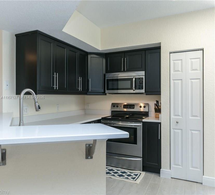 A kitchen features black cabinets, stainless steel appliances, and a white countertop peninsula — NORTH LAUDERDALE, FL
