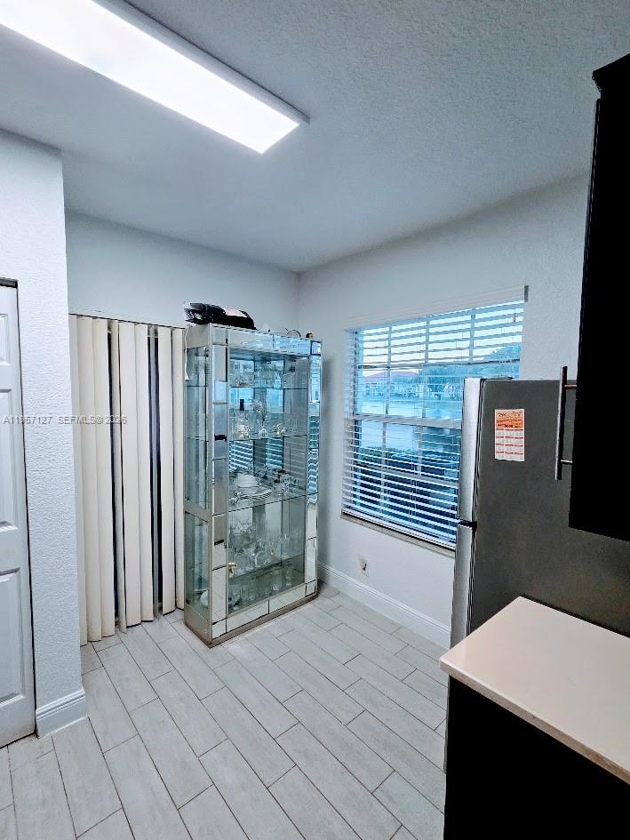 A kitchen area features light wood-look tile flooring, a mirrored display cabinet, and a window — NORTH LAUDERDALE, FL