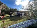 A view of a house exterior with a grassy lawn and a white fence — 809 N JOHN YOUNG PARKWAY, KISSIMMEE, FL