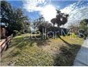 A grassy yard with trees and a wooden fence under a bright, sunny sky — 809 N JOHN YOUNG PARKWAY, KISSIMMEE, FL