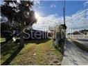 A view of a residential property exterior with a lawn, palm tree, and sidewalk — 809 N JOHN YOUNG PARKWAY, KISSIMMEE, FL