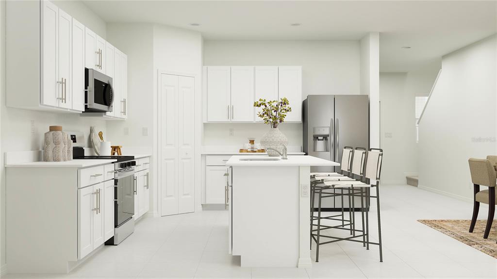 A bright kitchen features white cabinets, stainless steel appliances, a central island, and tile flooring — 1116 HOUR GLASS ROAD, LAKELAND, FL