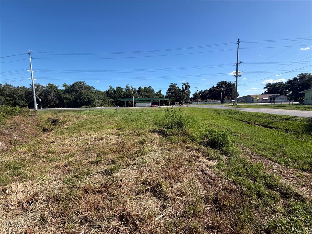 A vacant, grassy lot sits near a road with a gas station in the distance — DOSSEY ROAD S, LAKELAND, FL