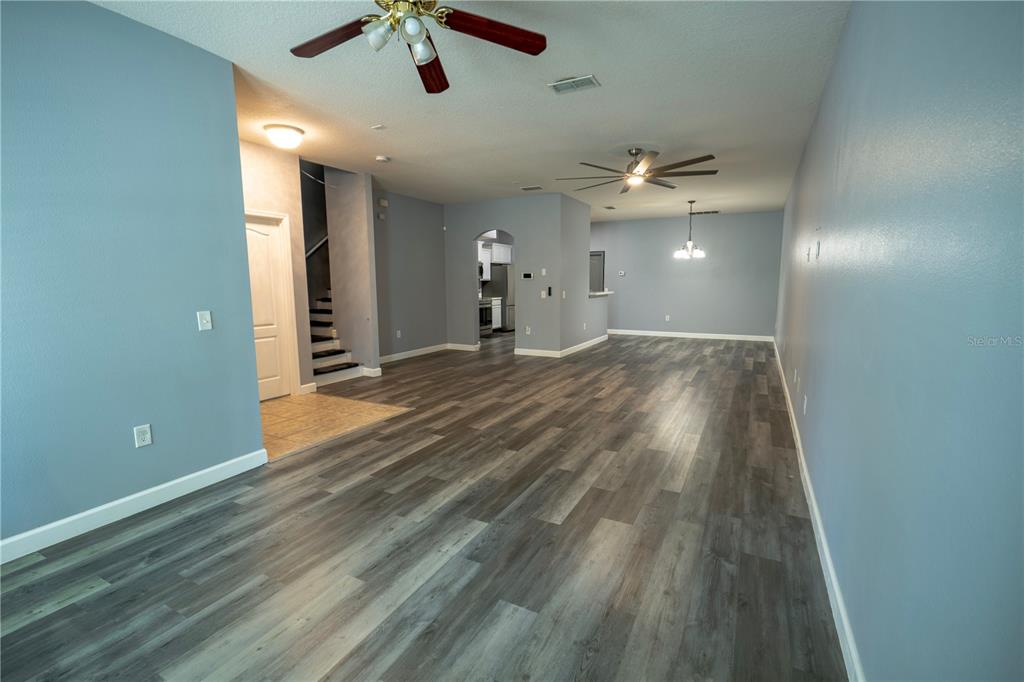 An open-concept living area features gray walls, wood-look flooring, and two ceiling fans — 2431 GRASMERE VIEW PARKWAY N, KISSIMMEE, FL