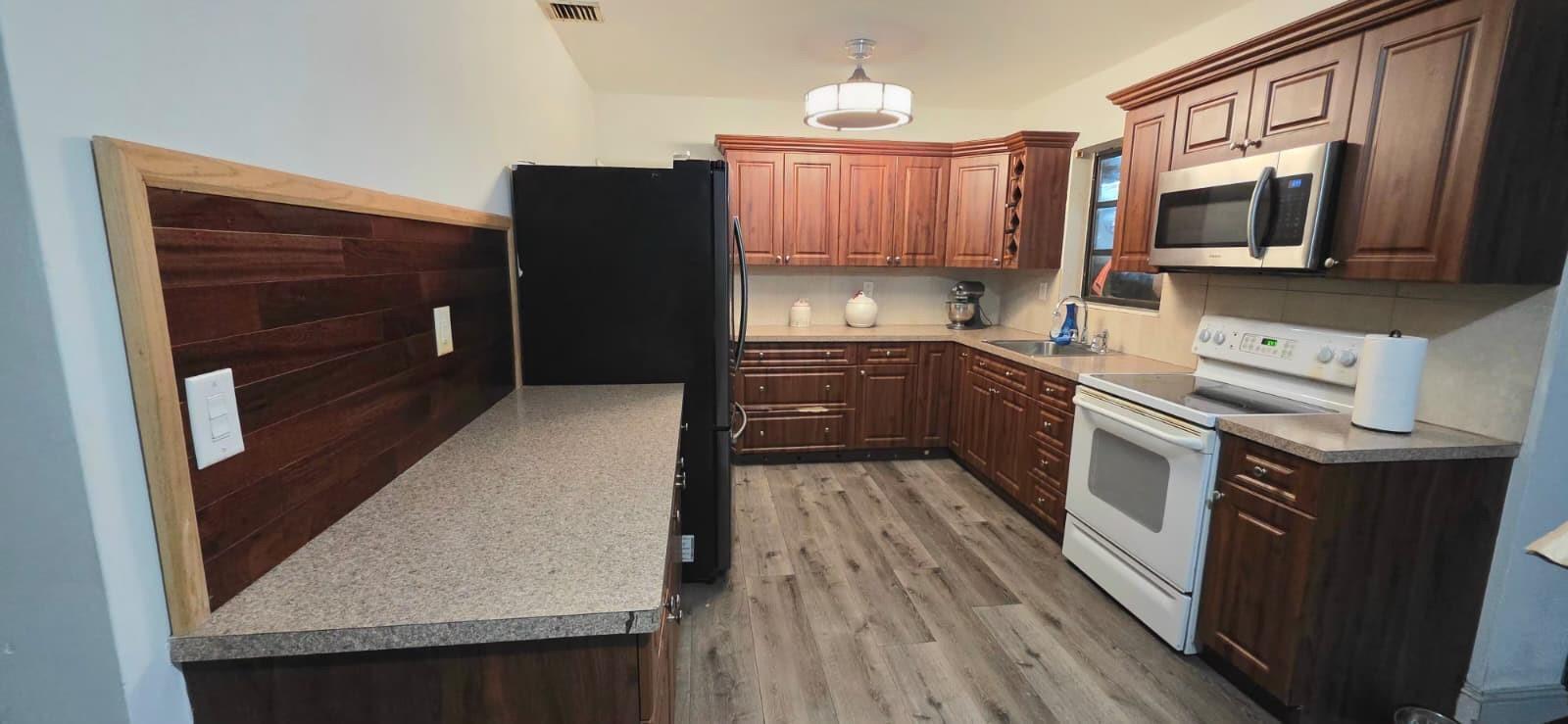 A kitchen features dark wood cabinets, a gray speckled countertop, and wood-look laminate flooring — 2701 Arcadia Drive, Miramar FL 33023, MIRAMAR, FL
