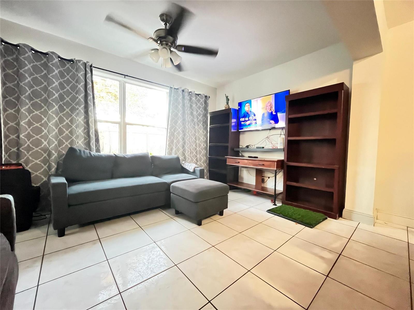 A living room features a gray sectional sofa, a wall-mounted television, and tile flooring — 2701 Arcadia Drive, Miramar FL 33023, MIRAMAR, FL