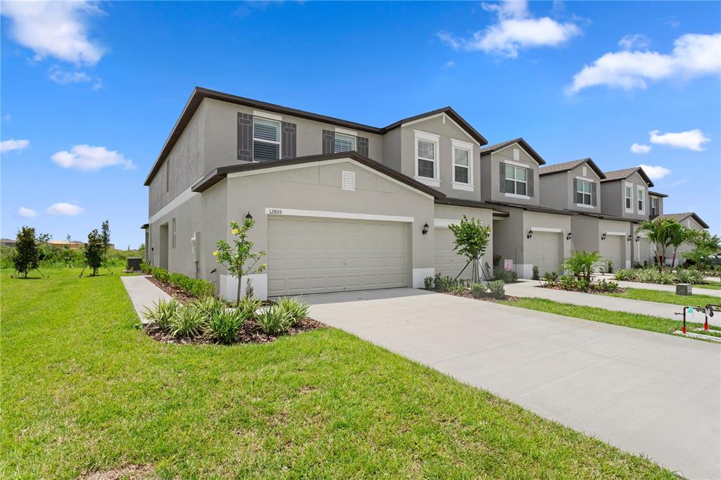 A row of modern two-story townhomes with beige stucco exteriors and attached garages — 12805 CRYSTAL JADE WAY, PARRISH, FL