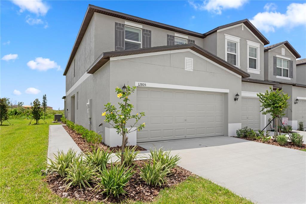 A two-story gray stucco townhouse with a two-car garage and a small front garden — 12805 CRYSTAL JADE WAY, PARRISH, FL