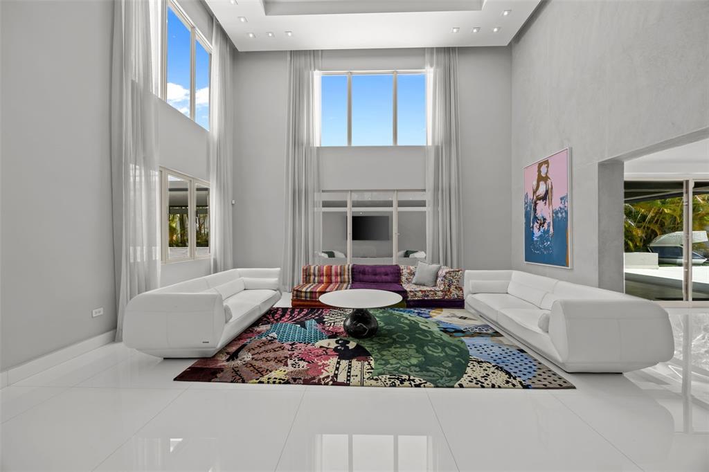 A spacious living room features high ceilings, white tile floors, two white sofas, and colorful furniture — 442 DORADO BEACH EAST, DORADO, PR
