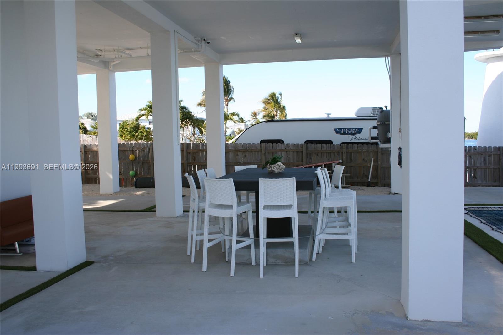 An outdoor patio features a dark dining table with white chairs under a covered structure — 1553 Sunrise Dr, Big Pine FL 33043, BIG PINE, FL