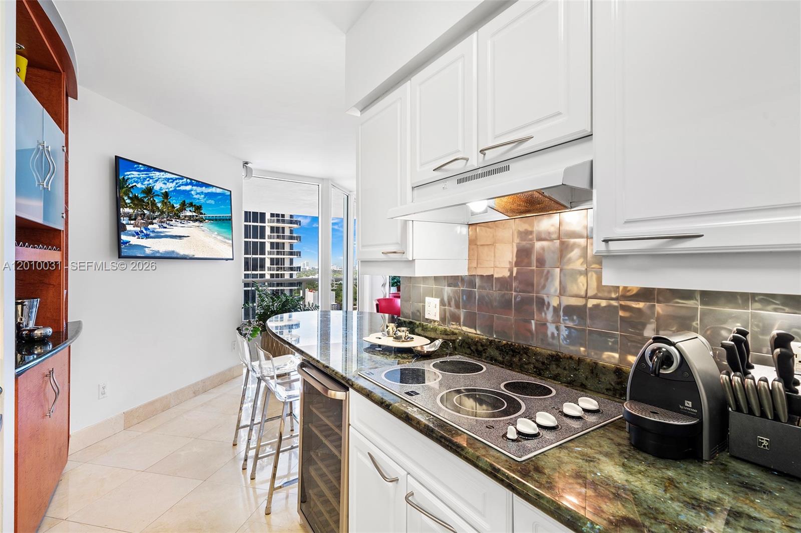 A kitchen features white cabinets, a dark granite countertop, a cooktop, and a balcony view — 4779 Collins Ave # 2404, Miami Beach FL 33140, MIAMI BEACH, FL