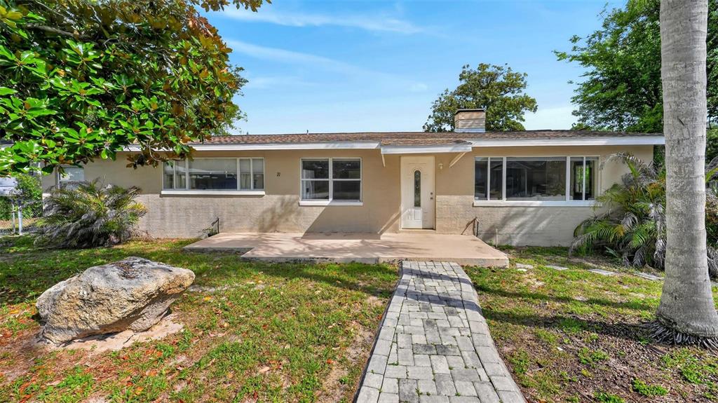 A single-story house with a beige exterior, a paved walkway, and a large front yard — 71 FAIRVIEW AVENUE, ORMOND BEACH, FL