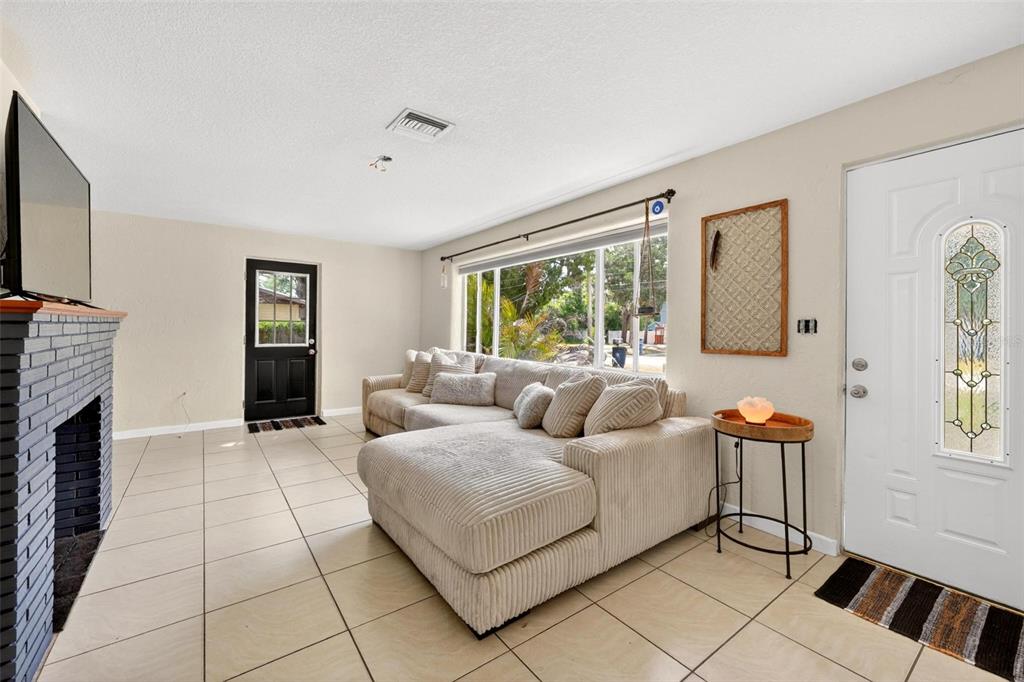 A living room features a large beige sectional sofa, a brick fireplace, and tile flooring — 71 FAIRVIEW AVENUE, ORMOND BEACH, FL