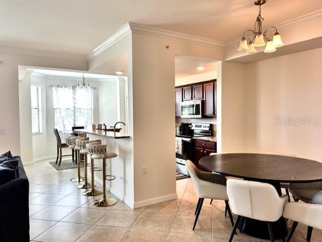 An open-concept dining area and kitchen feature a breakfast bar, tile flooring, and pendant lighting — 16804 VARDON TERRACE UNIT 102, BRADENTON, FL