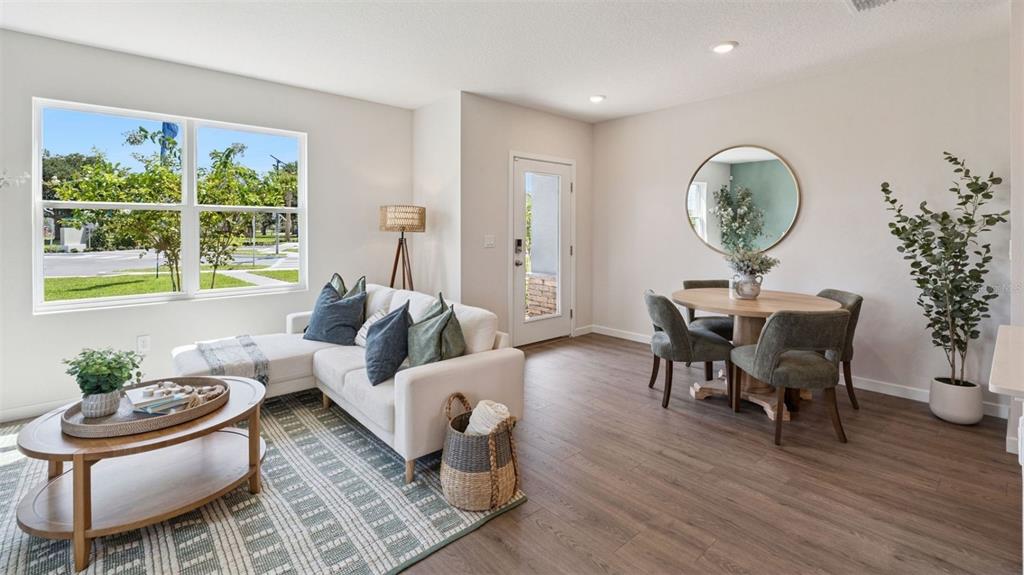 A bright living and dining area features wood-look flooring, a white sectional, and round table — 2247 RITA LANE, KISSIMMEE, FL