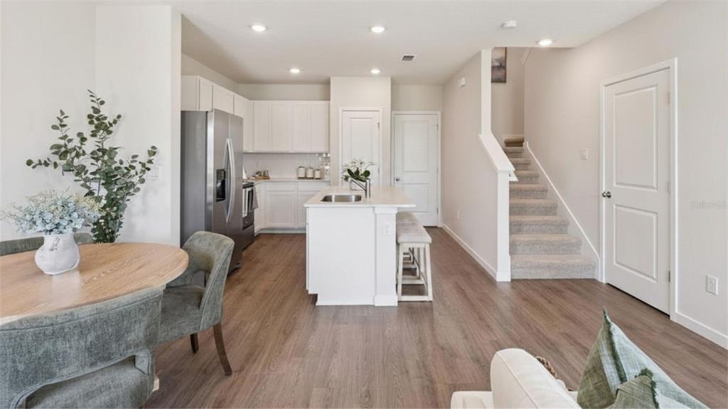 A kitchen with white cabinets, a center island, and stairs leading to an upper level — 2247 RITA LANE, KISSIMMEE, FL