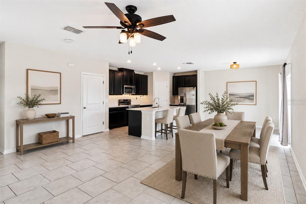 A kitchen features dark wood cabinets, stainless steel appliances, and a white quartz island countertop — 310 CITRUS POINTE DRIVE, DAVENPORT, FL