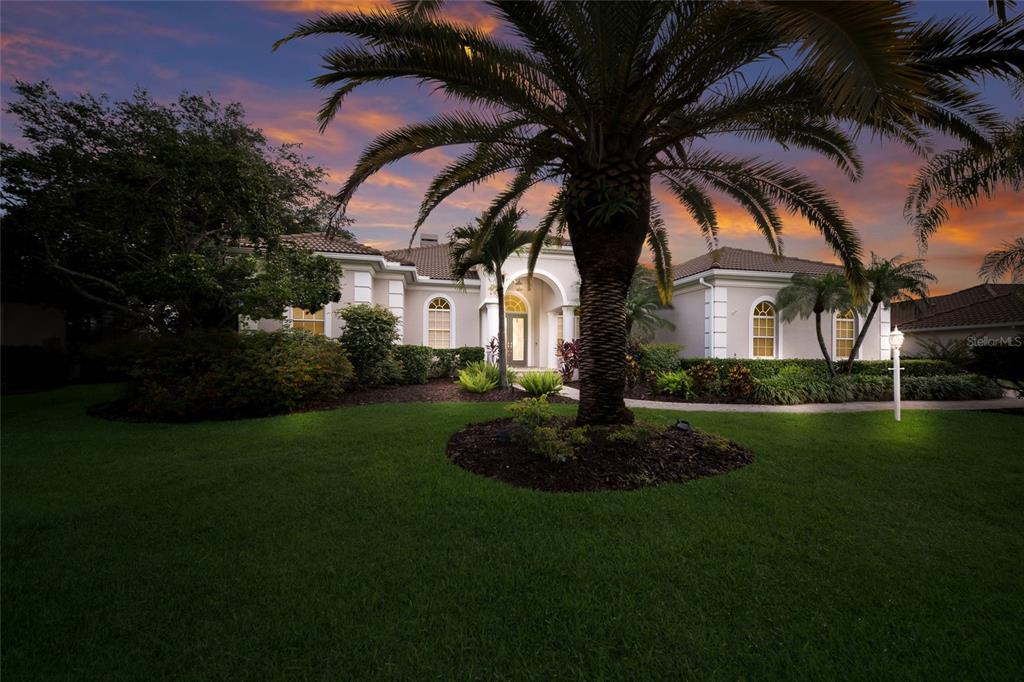 A single-story house with a palm tree in the front yard at sunset — 7920 ROYAL QUEENSLAND WAY, LAKEWOOD RANCH, FL