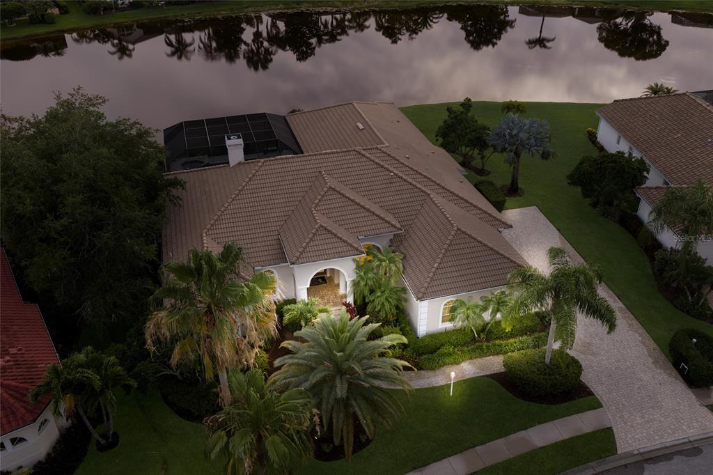 An aerial view of a single-story house with a tiled roof, pool cage, and landscaping — 7920 ROYAL QUEENSLAND WAY, LAKEWOOD RANCH, FL