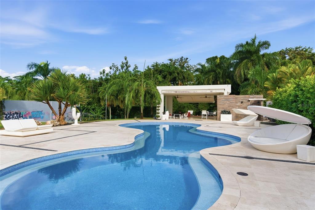 A kidney-shaped swimming pool sits on a stone patio with lounge chairs and a pavilion — 85 ORQUIDIA, SAN JUAN, PR