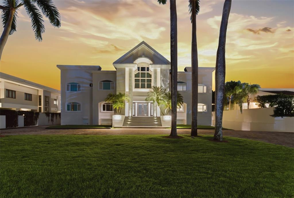 A large two-story house with a central staircase and palm trees at sunset — 85 ORQUIDIA, SAN JUAN, PR