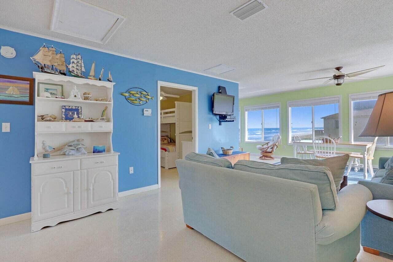 A living room with blue walls, a white hutch, and ocean views through large windows — 1501 NE Ocean Boulevard # 2, Stuart FL 34996, STUART, FL