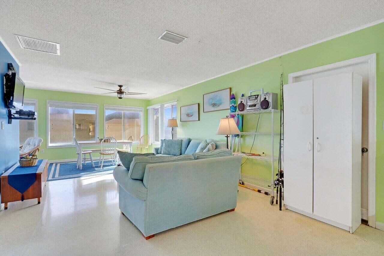 A living room with light green walls, a blue sofa, and a dining area — 1501 NE Ocean Boulevard # 2, Stuart FL 34996, STUART, FL