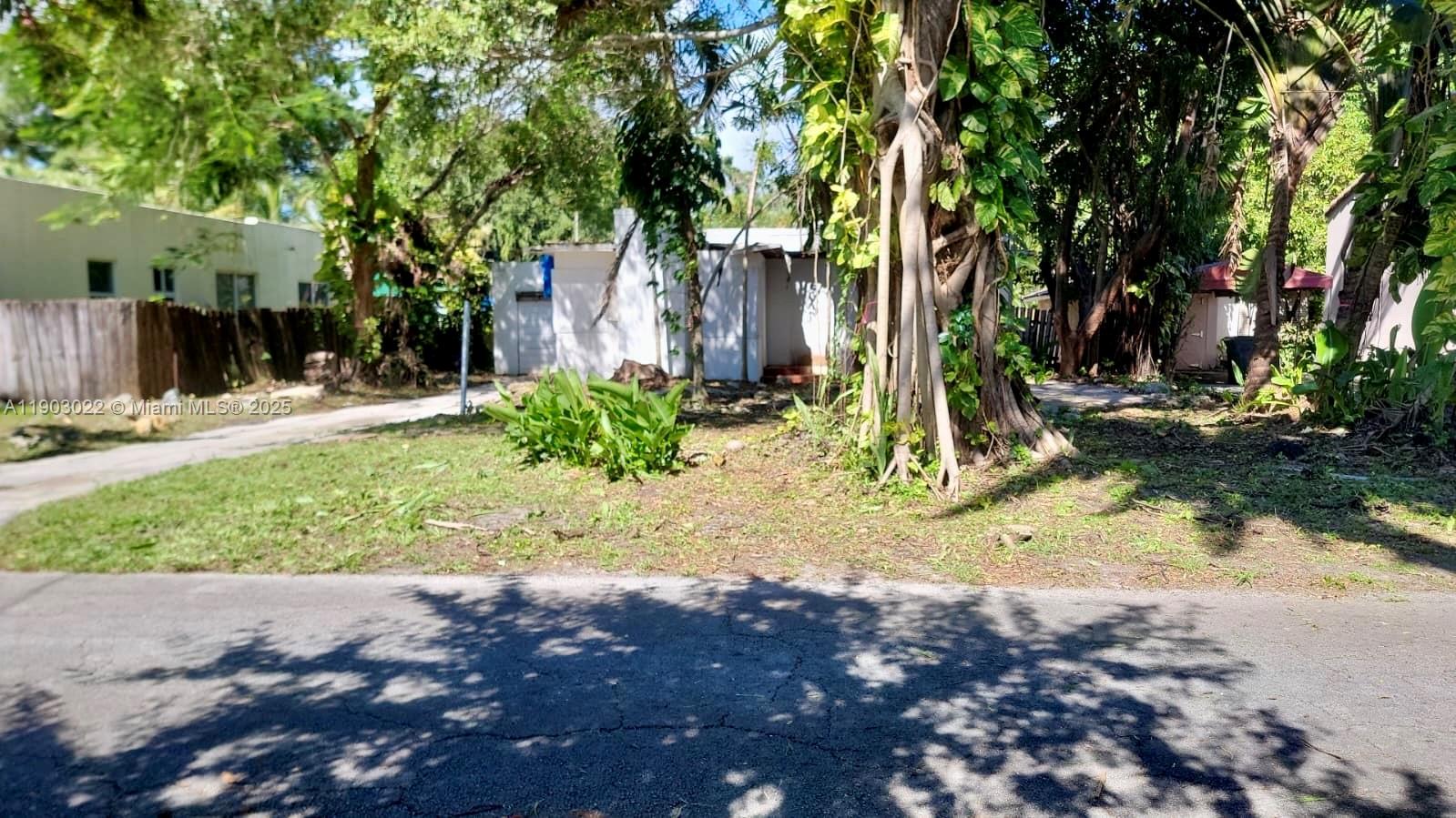 A white house sits behind a large tree with exposed roots and a grassy yard — 519 NE 118th St, Biscayne Park FL 33161, BISCAYNE PARK, FL