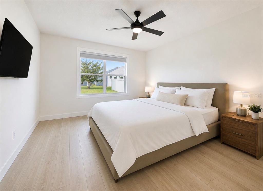 A bedroom features a bed with white bedding, light wood flooring, and a ceiling fan — 13518 PARKFIELD WAY, WINTER GARDEN, FL