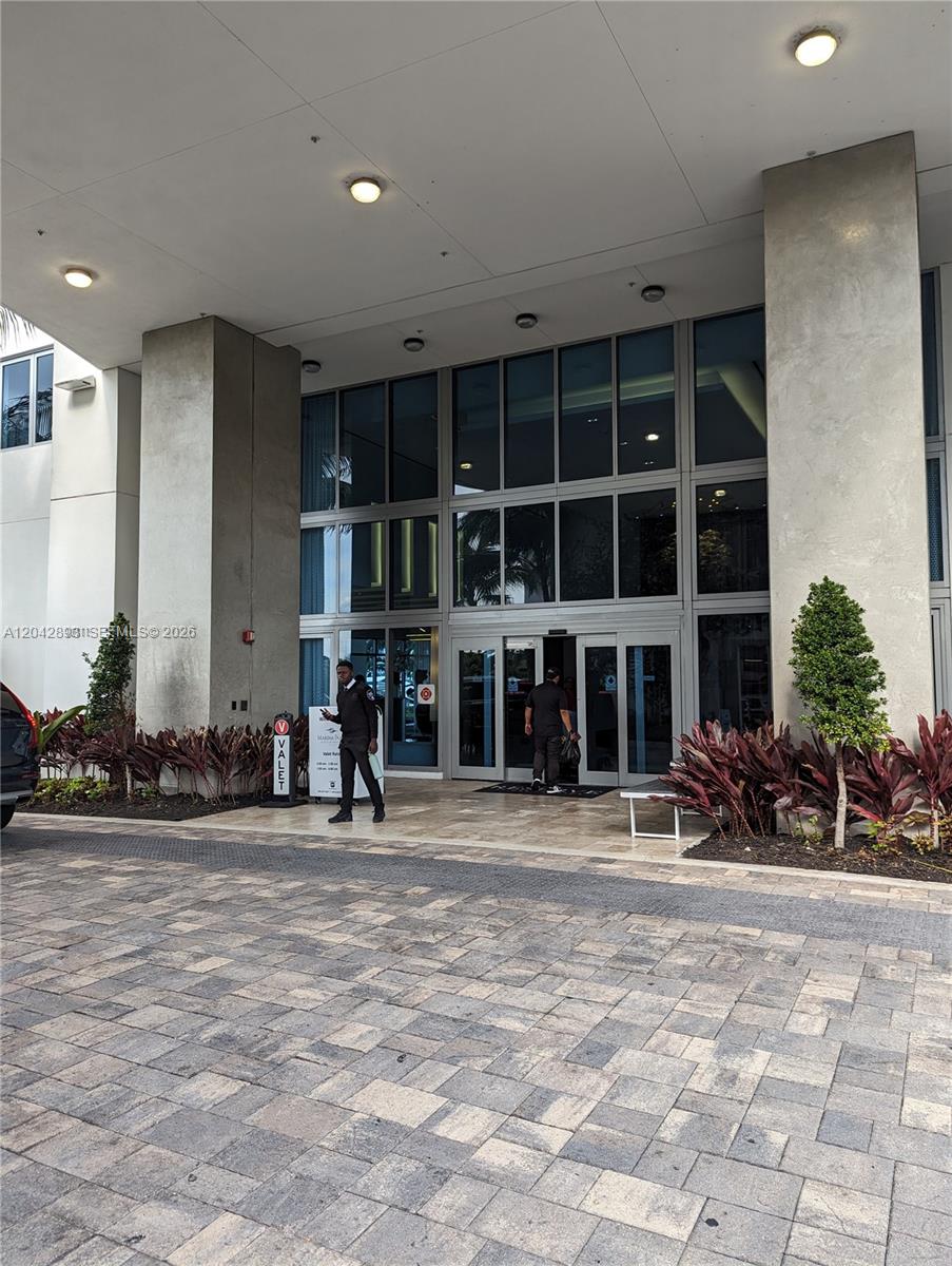 The exterior entrance of a building features a paved driveway, glass doors, and valet signage — 17111 E Biscayne Blvd # 1011, North Miami Beach FL 33160, NORTH MIAMI BEACH, FL