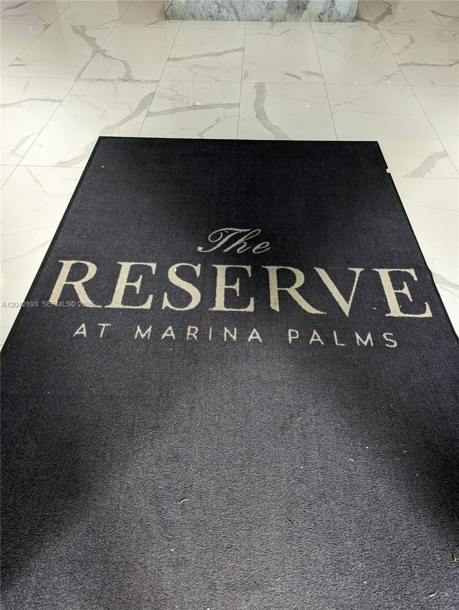 A black floor mat with the text The Reserve at Marina Palms sits on white tile — 17111 E Biscayne Blvd # 1011, North Miami Beach FL 33160, NORTH MIAMI BEACH, FL