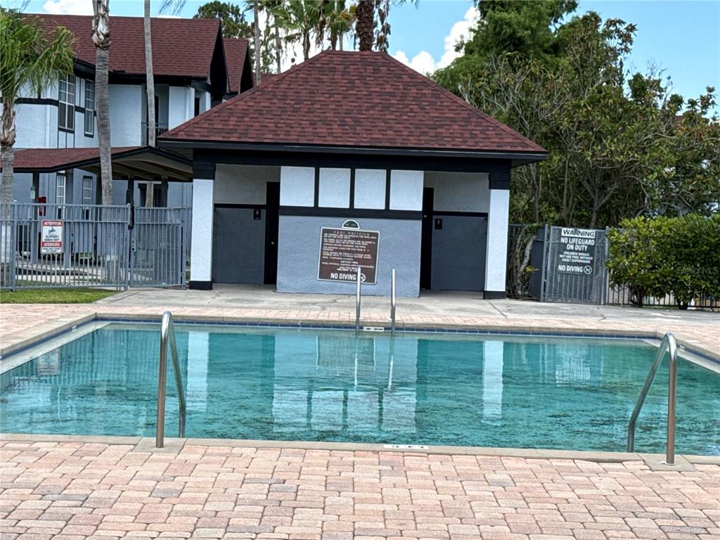 A rectangular swimming pool sits in front of a small building with a tiled roof — 3725 CASTLE PINES LANE UNIT 4322, ORLANDO, FL