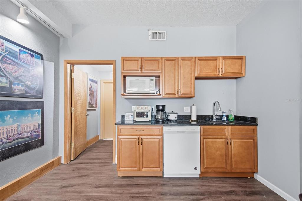 A small kitchen features light wood cabinets, a dishwasher, and a black countertop — 101 PALM HARBOR PARKWAY UNIT OB2, PALM COAST, FL